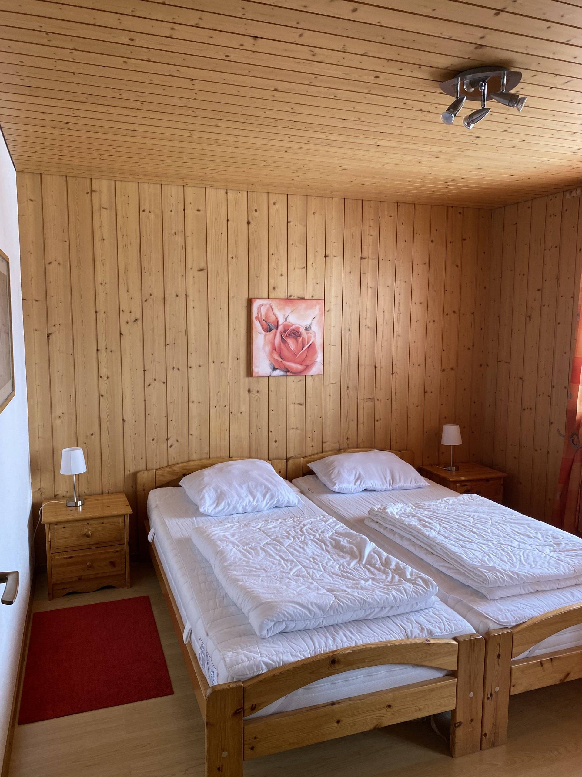 Elternzimmer mit zwei Betten, Nachttischen und Holztäfer