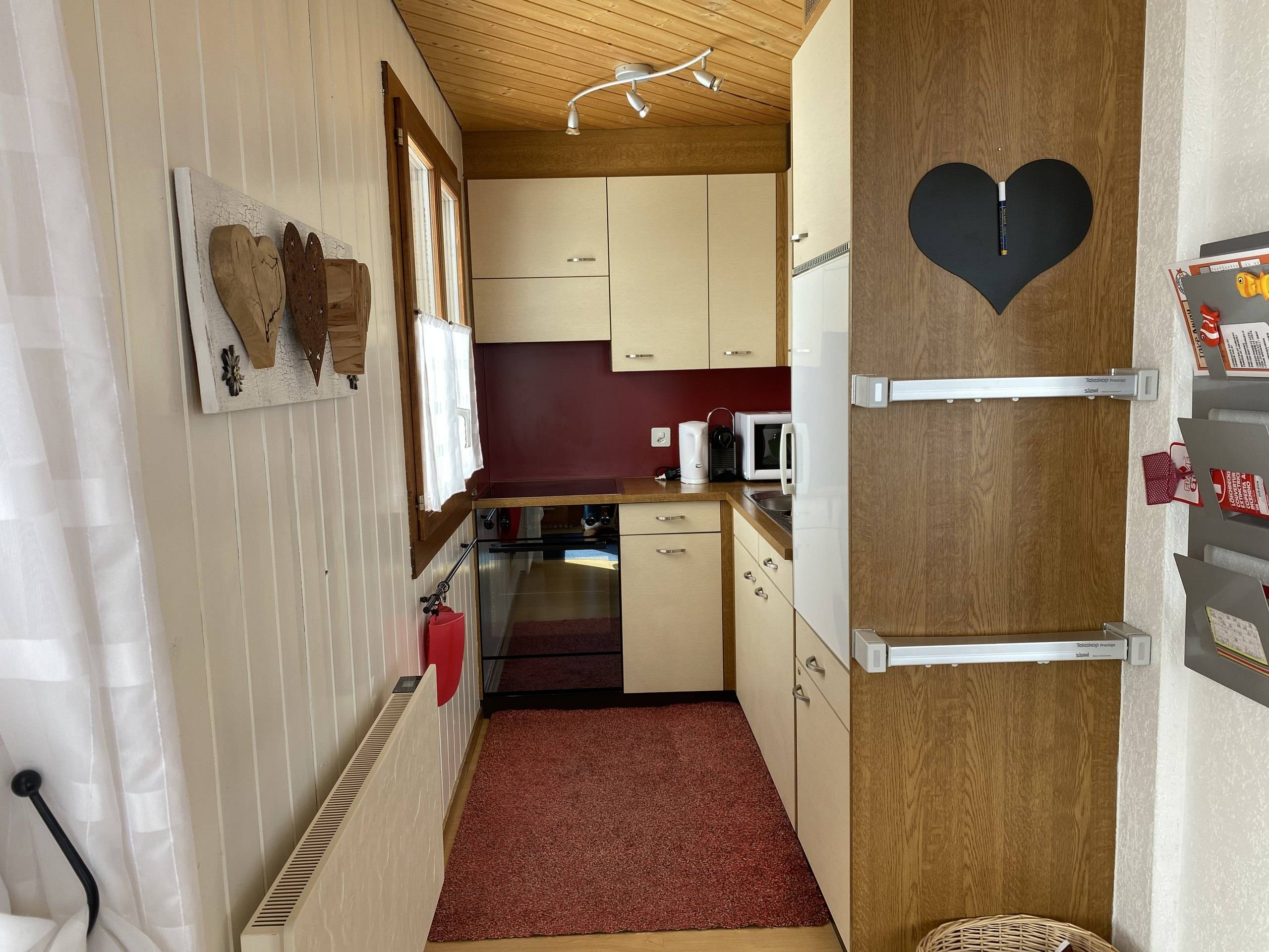 Schmale Küche mit Backofen, Kühlschrank und Holzschrank mit Herz