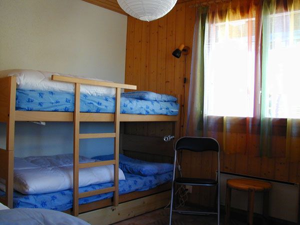Schlafzimmer mit Kajütenbett, Holzwänden und Fenster mit farbigen Vorhängen