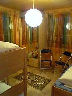 Schlafzimmer mit Bett, Holzwand und Hängelampe