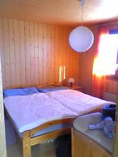 Schlafzimmer mit Doppelbett, Holztäfer und runder Hängelampe