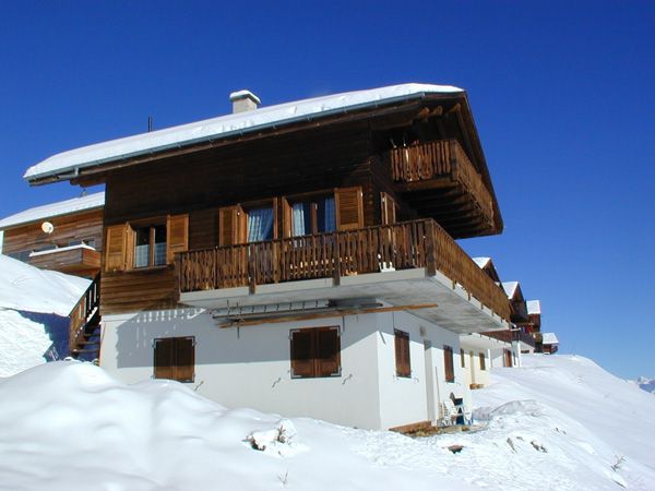 Chalet Bärgwind mit verschneitem Dach und Holzbalkon im Winter