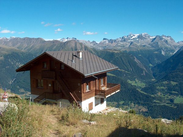 Chalet Bärgwind mit braunem Dach und Balkon über dem Tal im Sommer