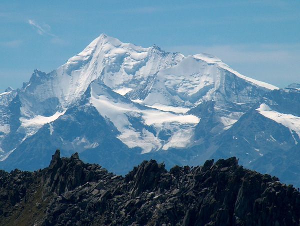 Verschneites Weisshorn unter blauem Himmel, im Vordergrund dunkle Felsgrate